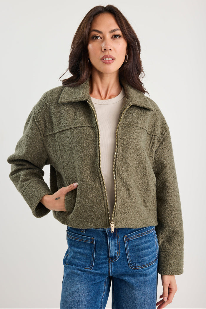 Woman wearing a green jacket and blue jeans on a white background