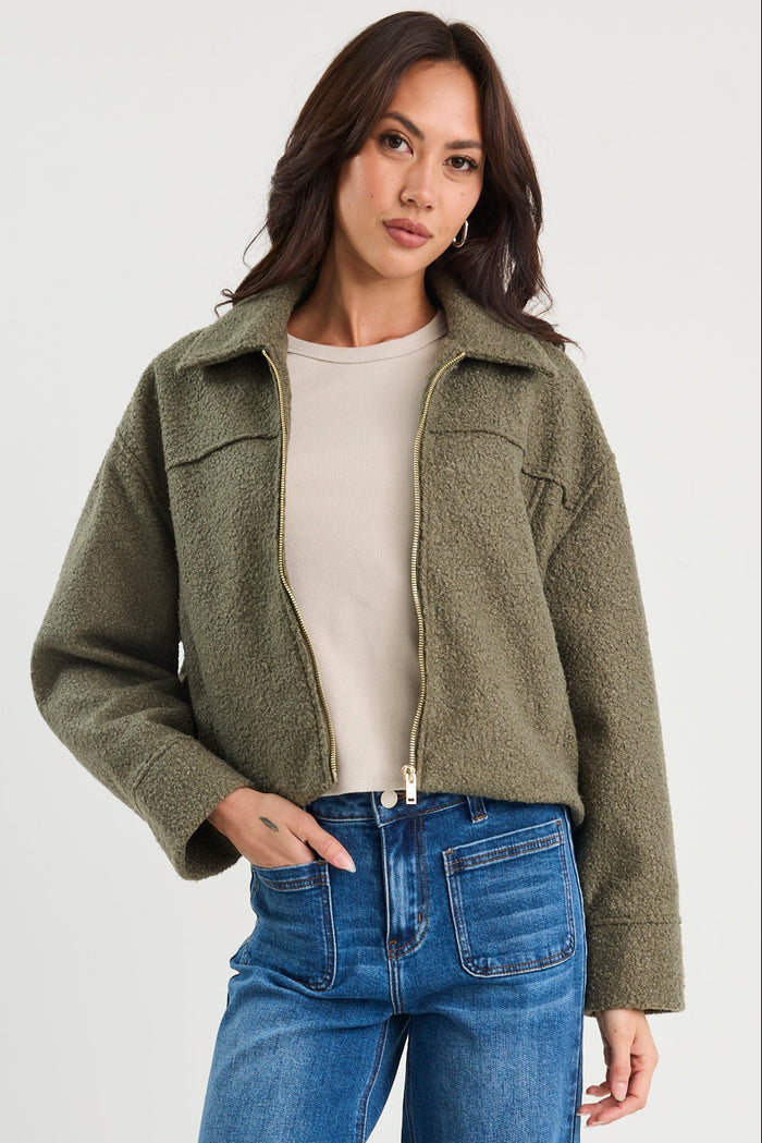 Woman wearing a green jacket and blue jeans on a white background