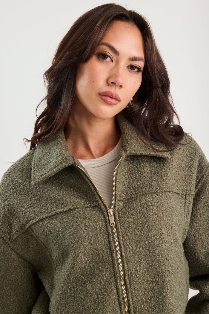 Woman wearing a green jacket against a white background