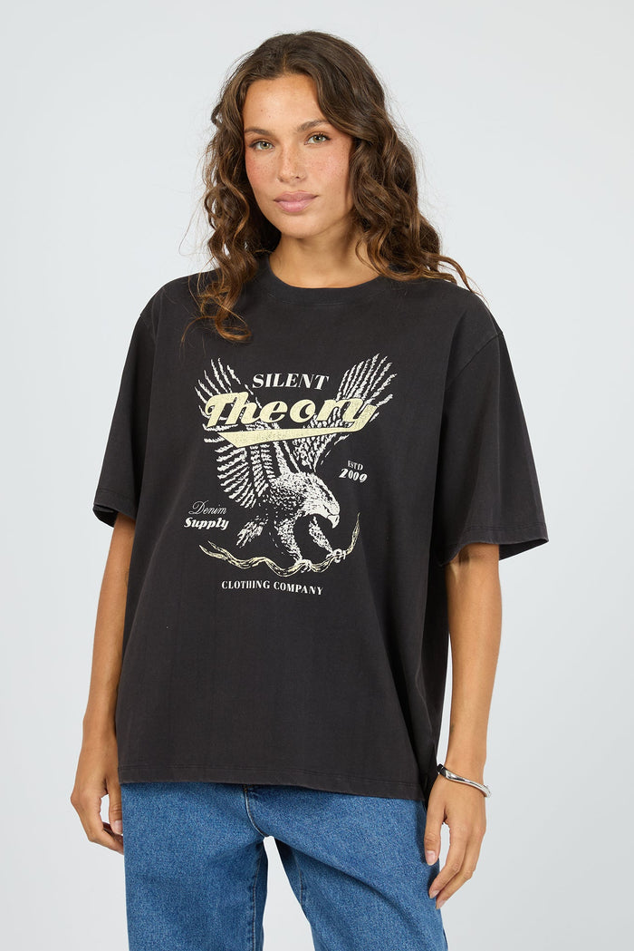 Woman wearing a black t-shirt with a graphic design on a plain background