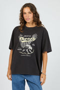 Woman wearing a black t-shirt with a graphic design on a plain background