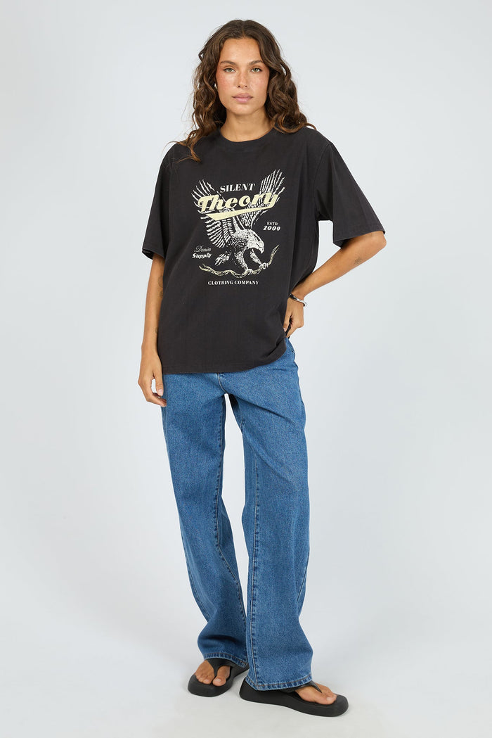 Person wearing a black t-shirt with a graphic design and blue jeans on a white background