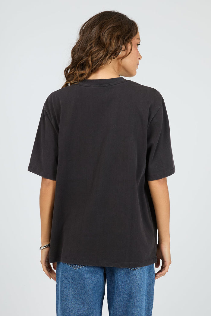 Person wearing a black t-shirt and blue jeans on a light gray background