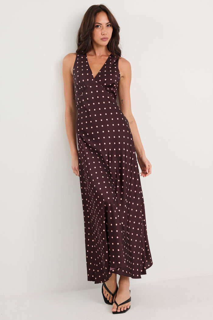 Woman wearing a long, dark patterned dress against a white background