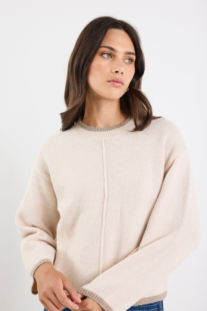 Woman wearing a beige sweater against a white background