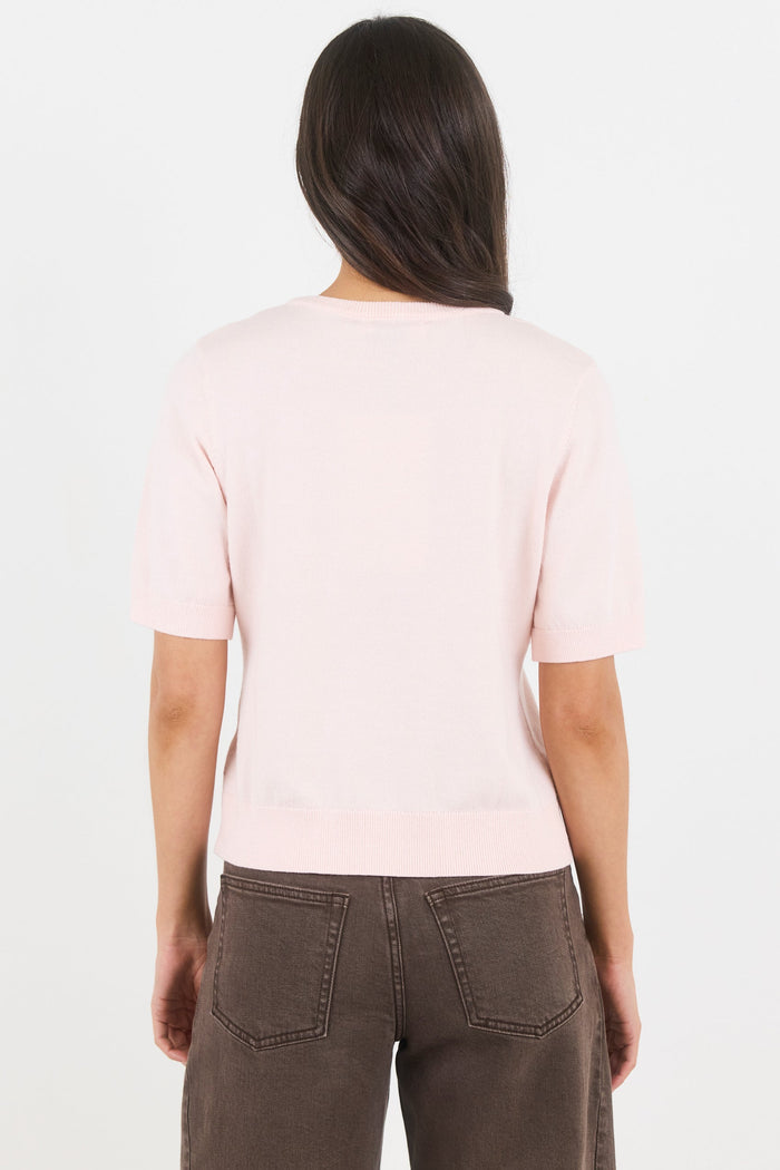 Person wearing a light pink t-shirt and brown pants on a white background