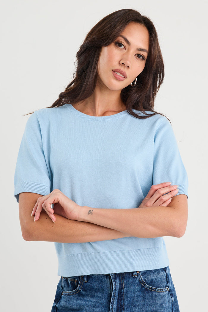 Woman wearing a light blue t-shirt and jeans against a white background