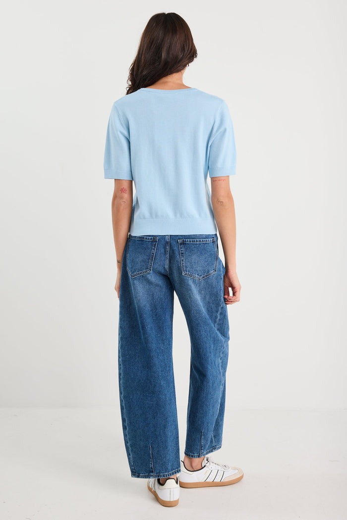 Person wearing a light blue sweater and dark blue jeans on a white background
