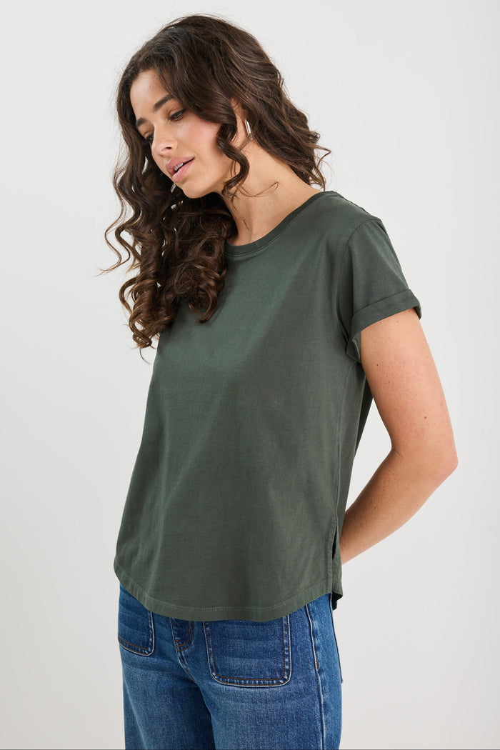 Woman wearing a green t-shirt and blue jeans on a white background