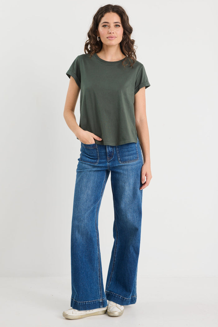 Woman wearing a green t-shirt and blue jeans on a white background