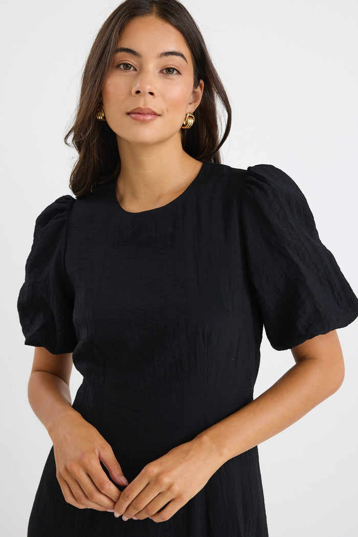 model wears a black puff sleeve midi dress