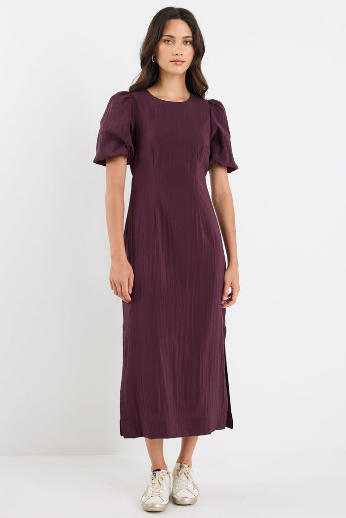 Woman wearing a purple dress with puffed sleeves on a white background