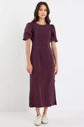 Woman wearing a purple dress with puffed sleeves on a white background