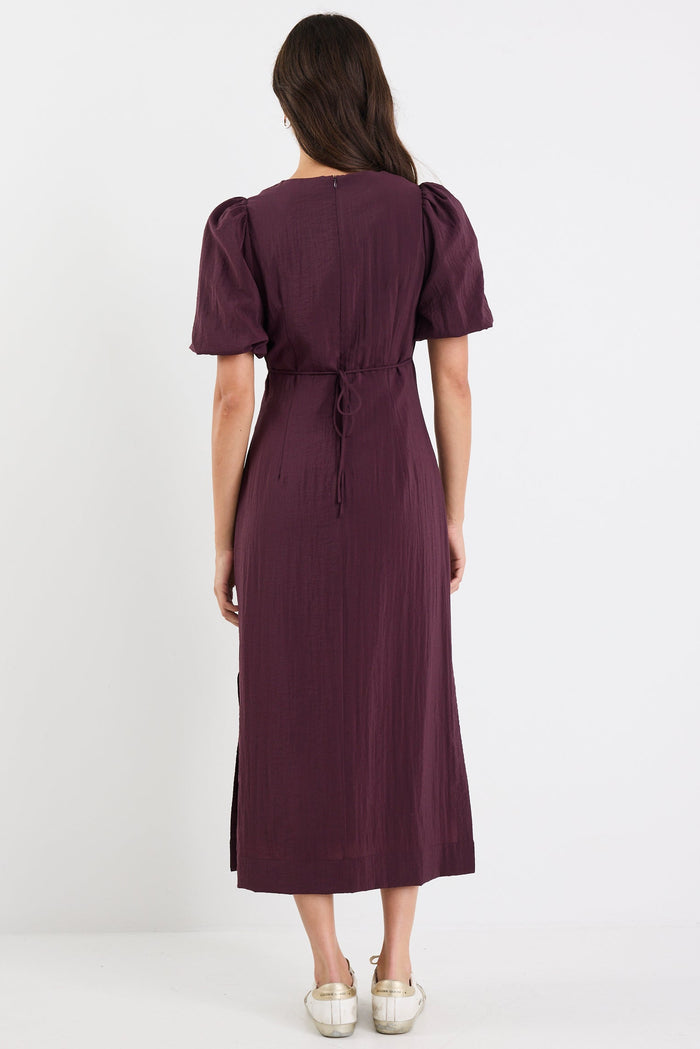Woman wearing a purple dress with puff sleeves on a white background