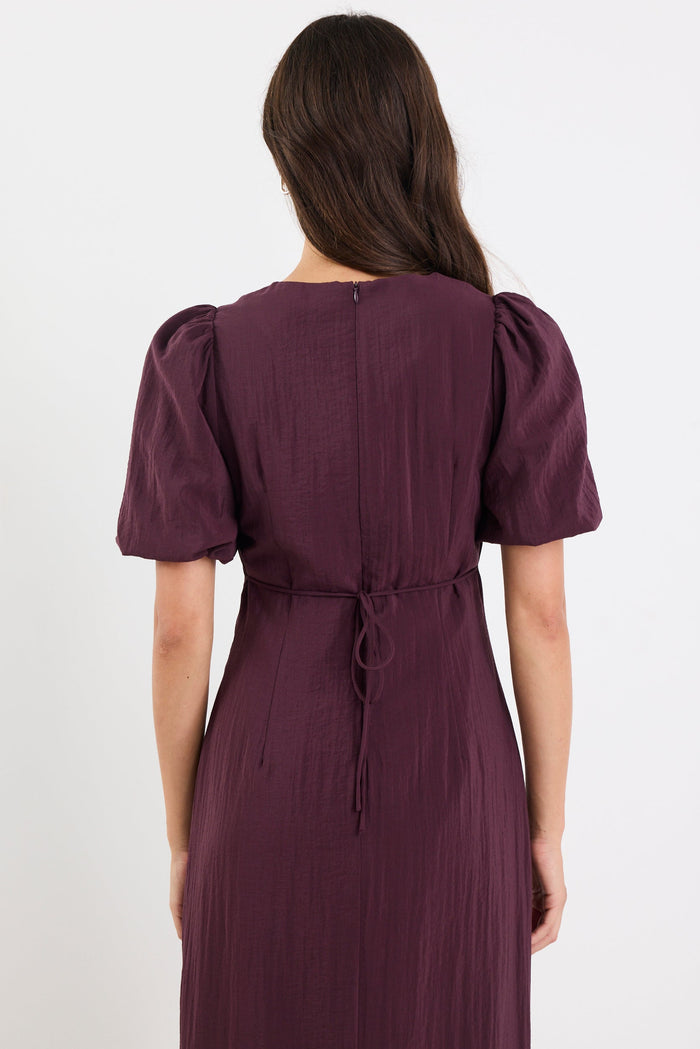 Woman wearing a purple dress with puff sleeves on a white background
