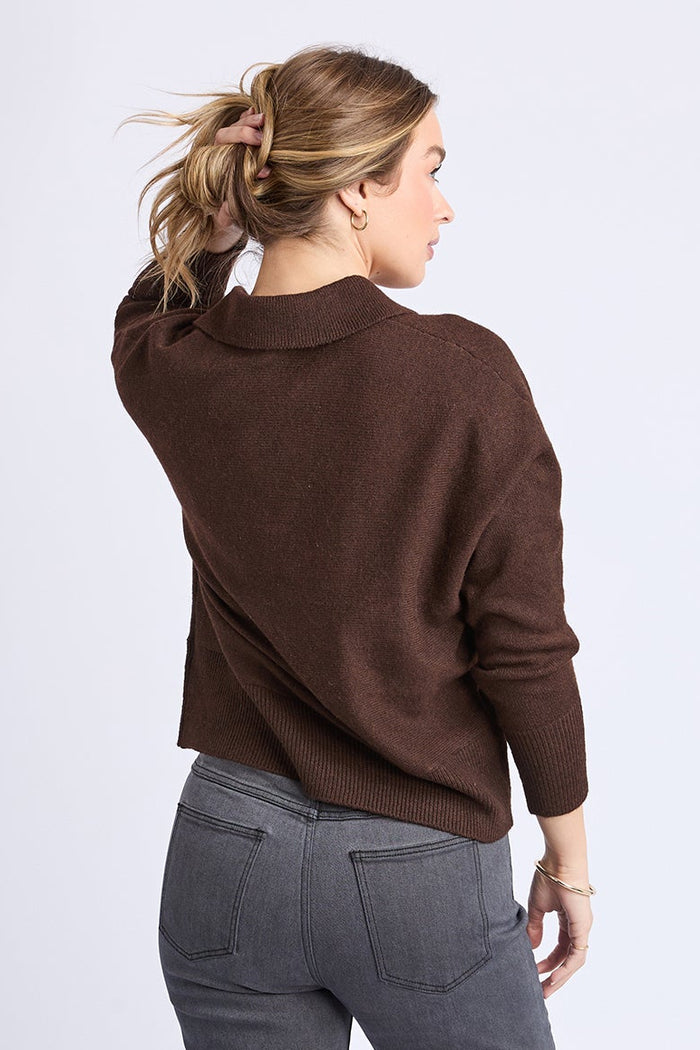 Woman wearing a brown sweater and gray pants on a white background