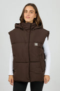 Woman wearing a brown puffer vest on a white background