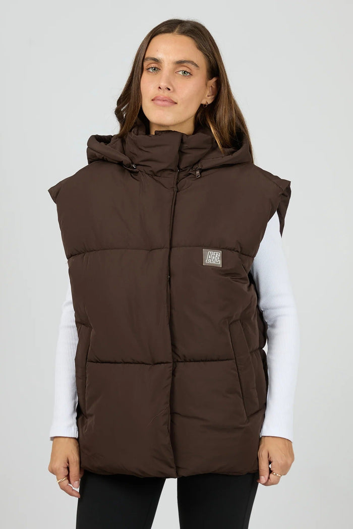 Woman wearing a brown puffer vest on a white background
