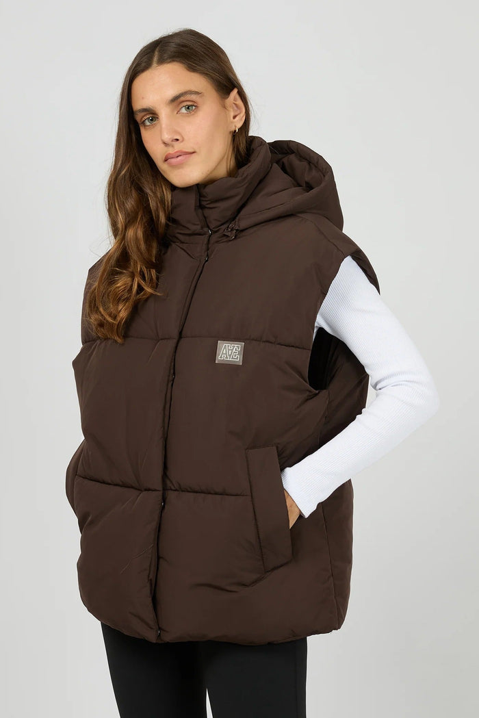 Woman wearing a brown puffer vest on a light gray background