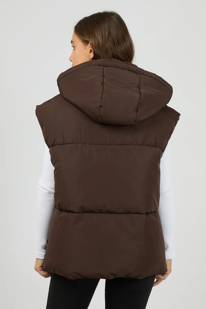 Woman wearing a brown puffer vest on a white background