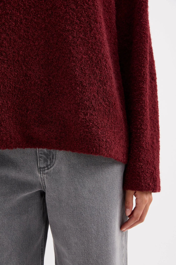 Maroon sweater worn by a person on a white background