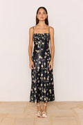 Woman wearing a black floral dress against a plain background