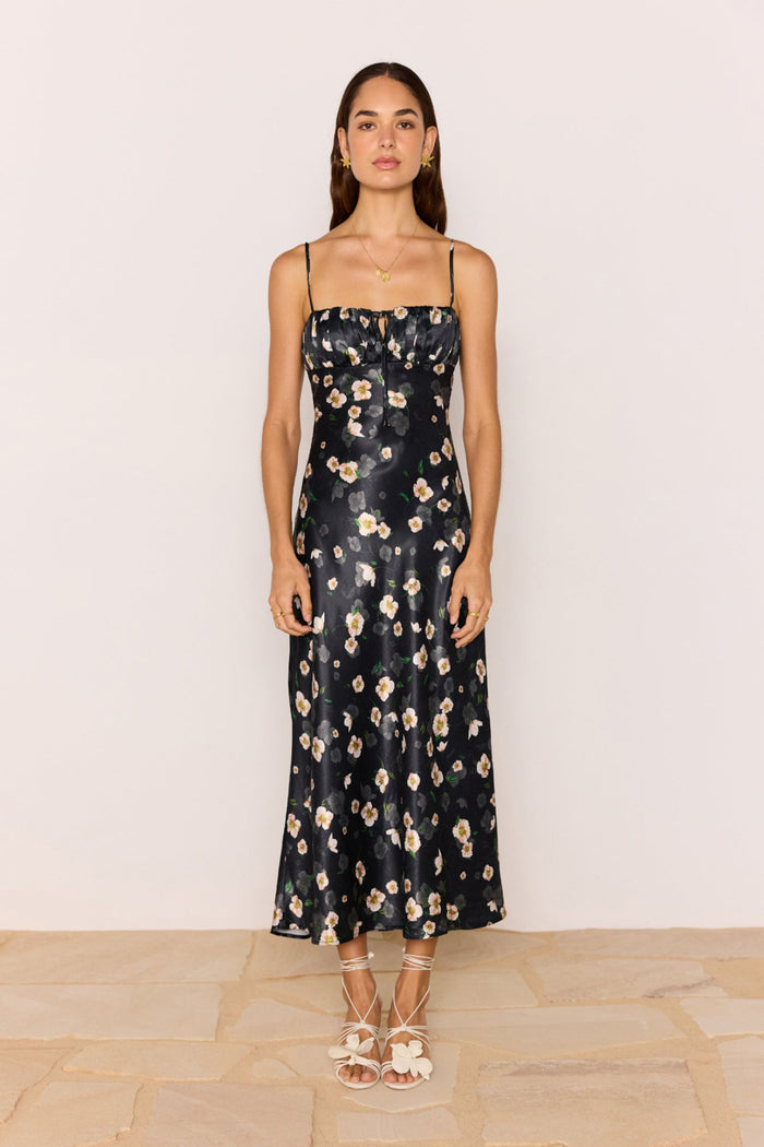Woman wearing a black floral dress against a plain background