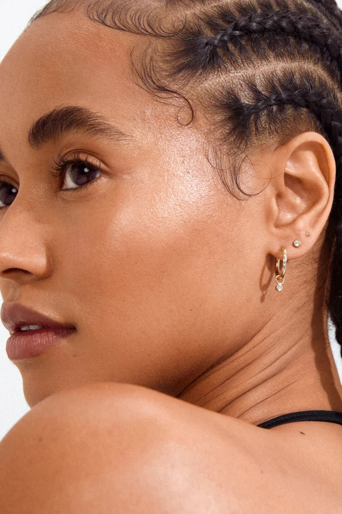 Close-up of a woman with braided hair wearing earrings on a white background
