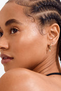 Close-up of a woman with braided hair wearing earrings on a white background
