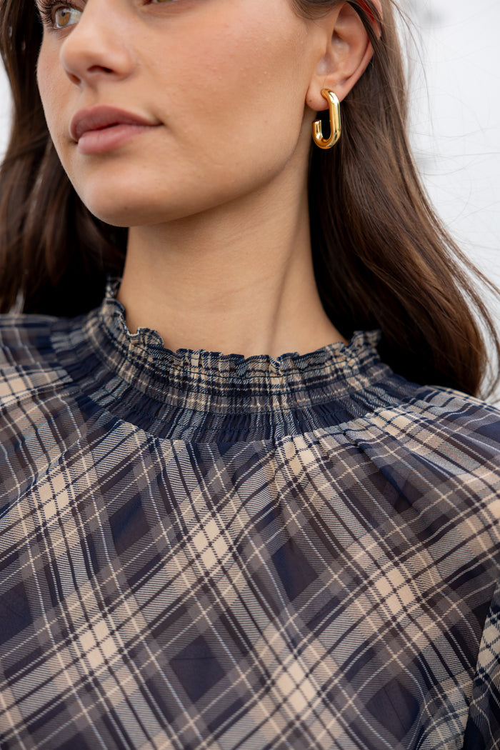 Close-up of a person wearing a plaid shirt with a blurred background