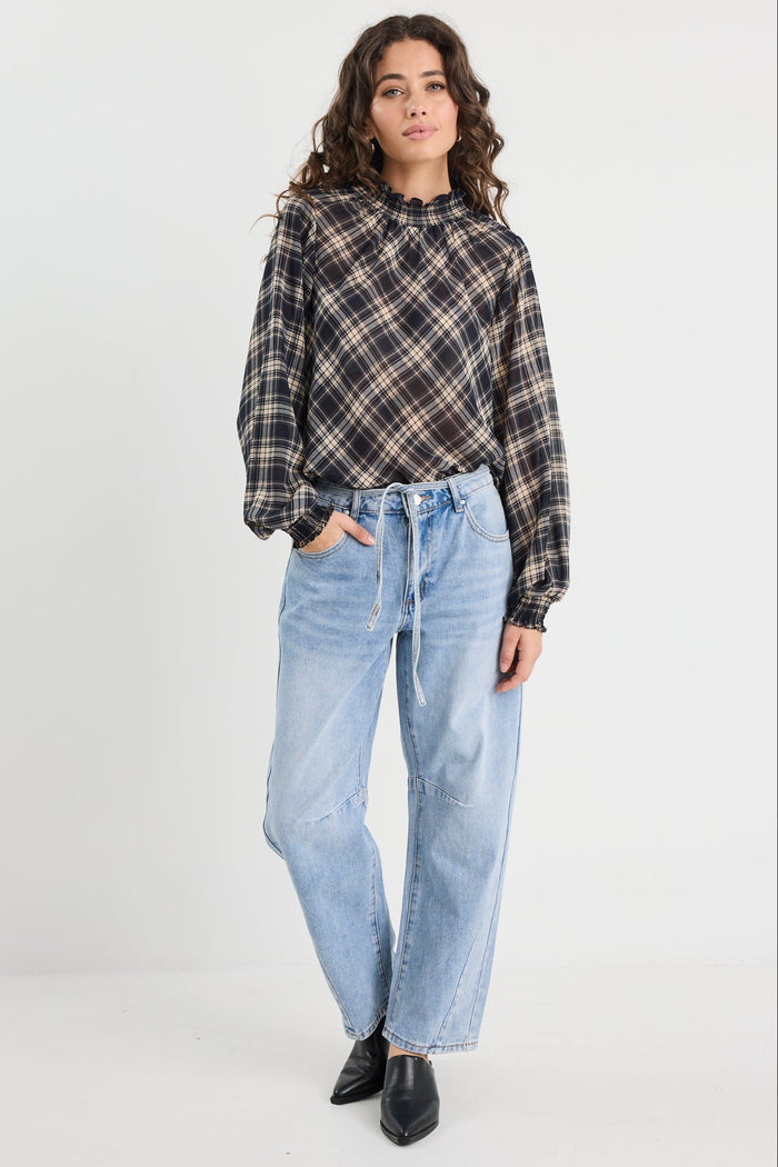 Person wearing a plaid shirt and light blue jeans on a white background