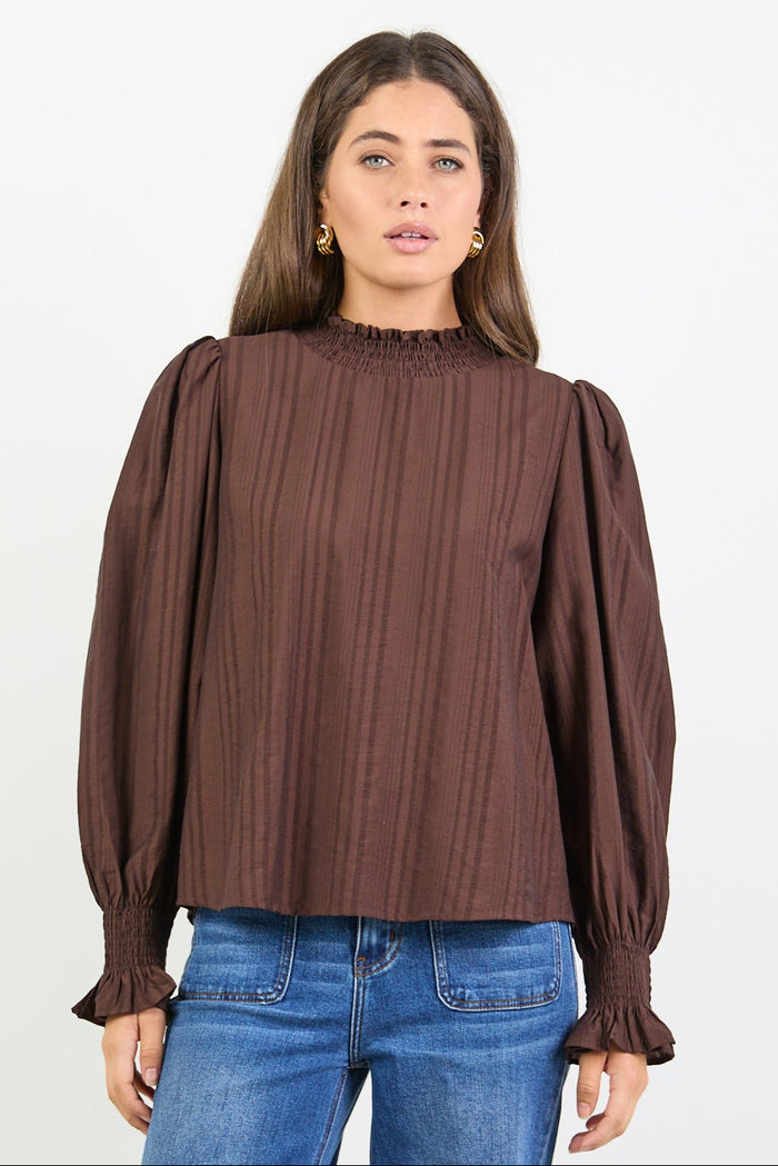 Woman wearing a brown blouse and blue jeans on a white background