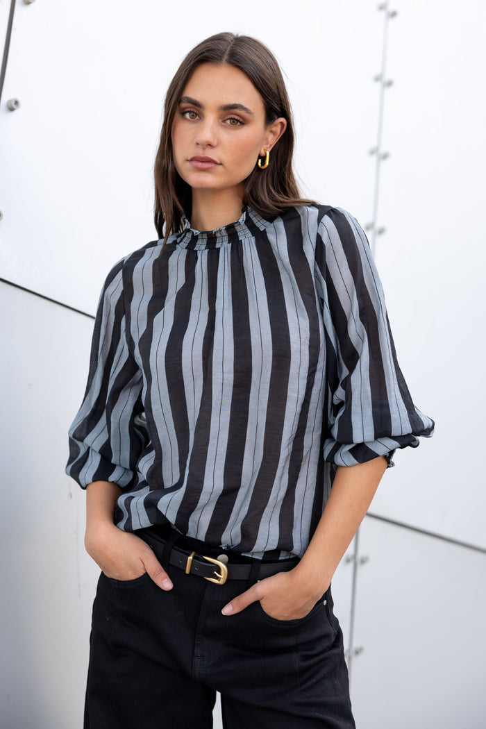 Woman wearing a black and gray striped blouse with a white background