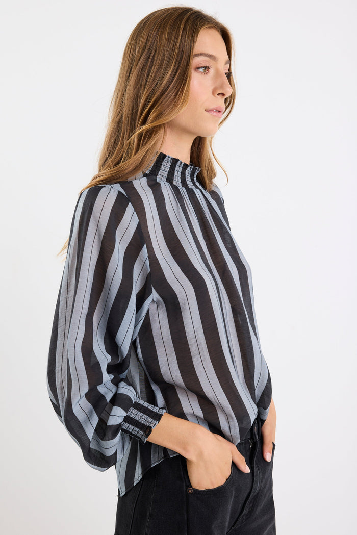 Woman wearing a black and gray striped blouse against a white background