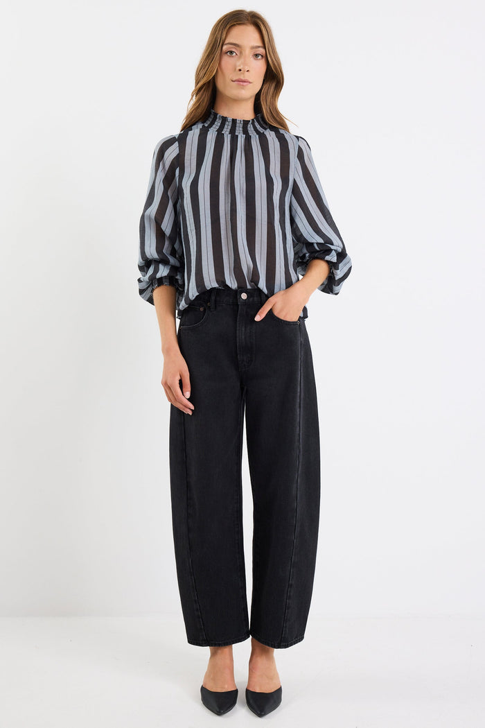 Woman wearing a black and white striped blouse and black pants on a white background