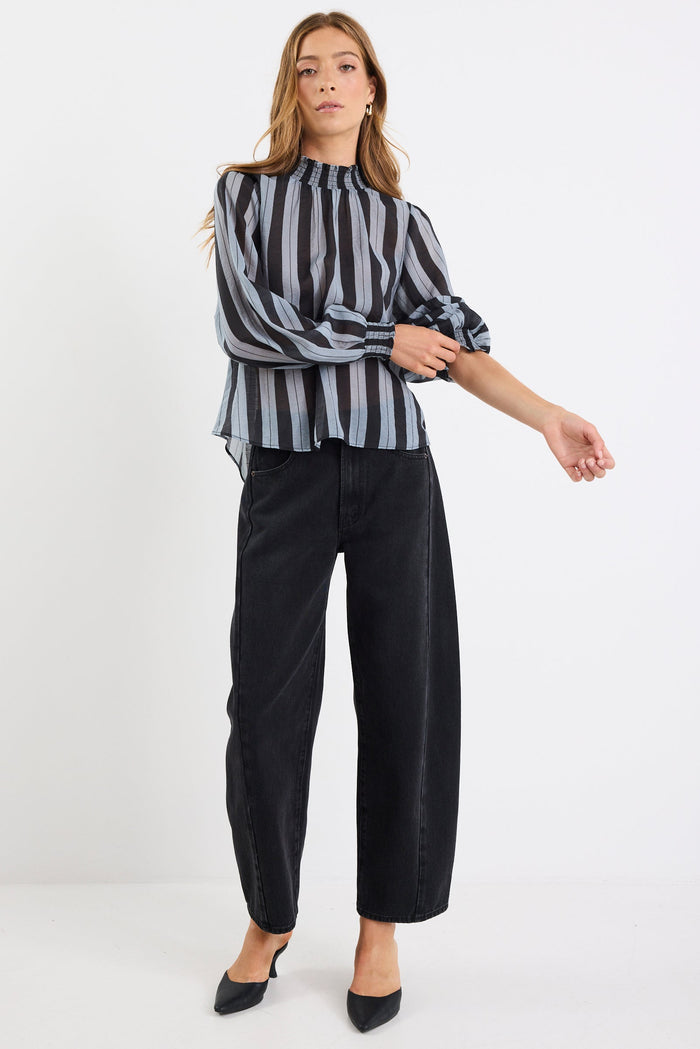 Woman wearing a striped shirt and black pants on a white background