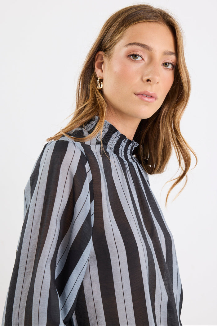 Woman wearing a black and gray striped shirt against a white background