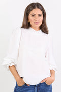 Woman wearing a white blouse and blue jeans against a white background