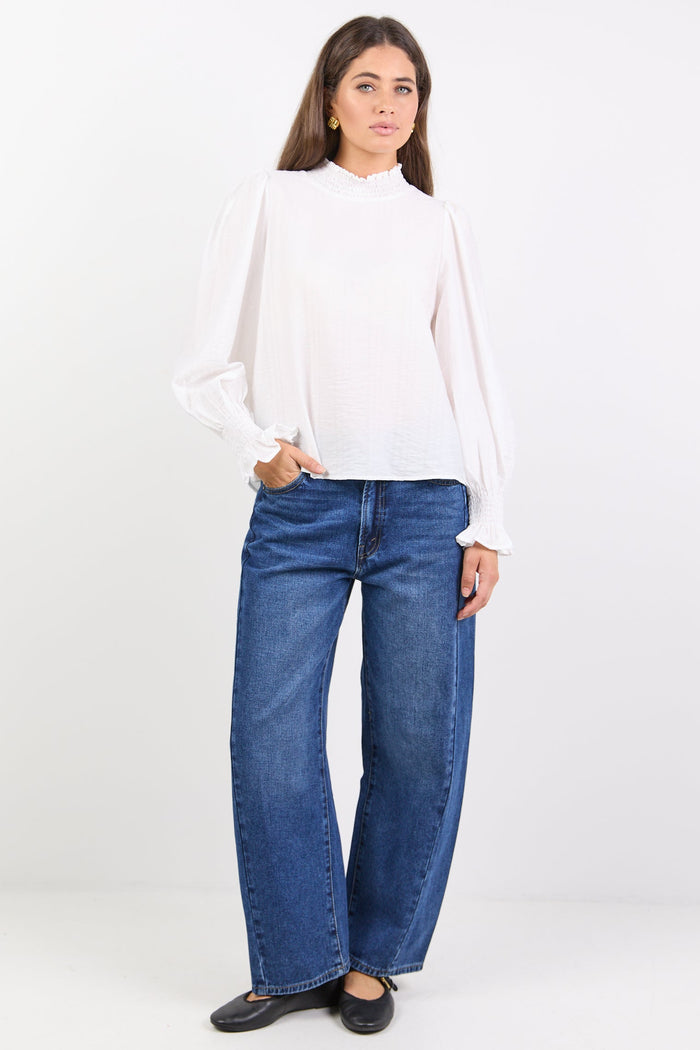 Woman wearing a white blouse and blue jeans on a white background
