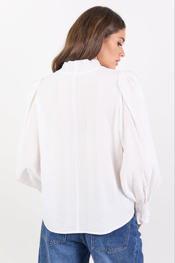 Woman wearing a white blouse and blue jeans on a white background