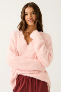 Woman wearing a pink fluffy sweater and red pants on a white background