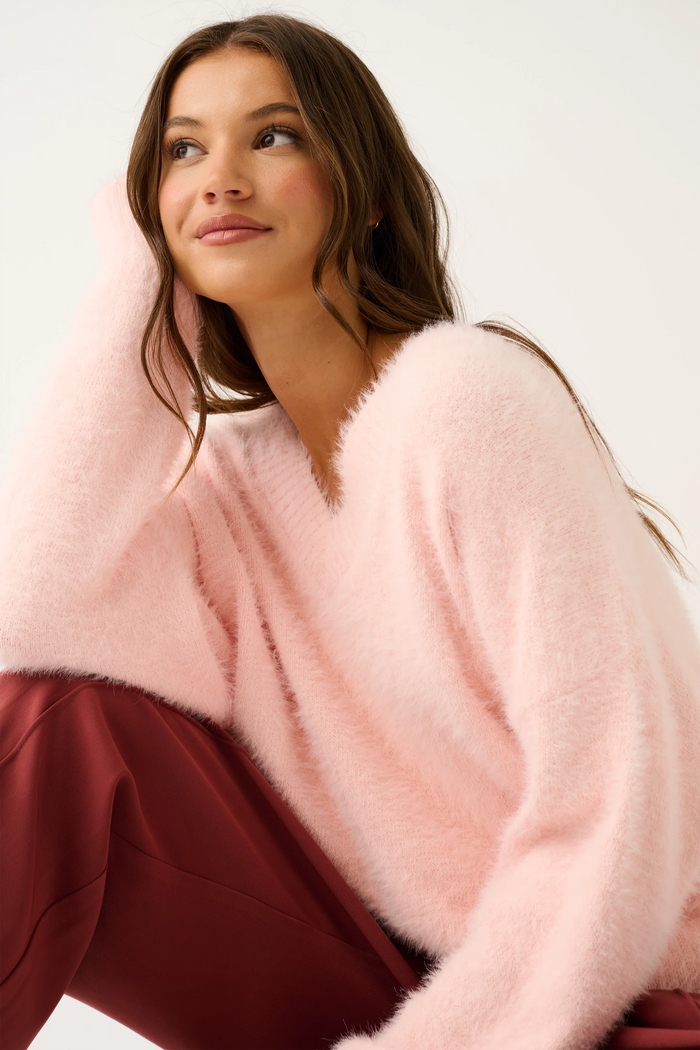 Woman wearing a pink fluffy cardigan against a white background