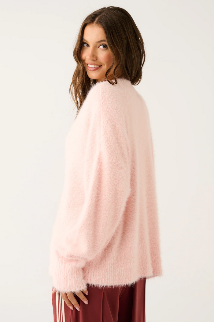 Woman wearing a light pink sweater against a white background