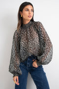 model wears a black animal print blouse with dark blue jeans