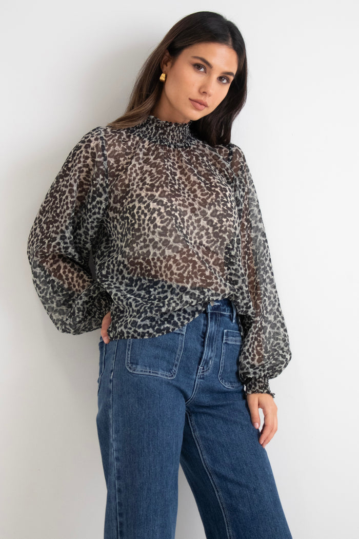model wears a black animal print blouse with dark blue jeans
