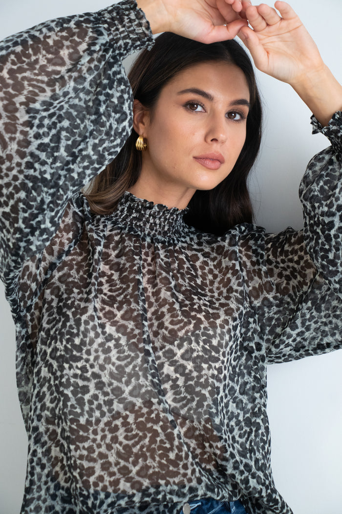 model wears a black animal print blouse with dark blue jeans