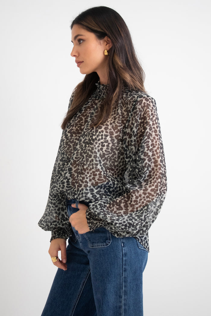 model wears a black animal print blouse with dark blue jeans