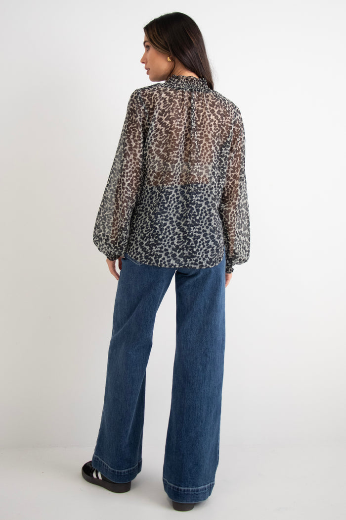 model wears a black animal print blouse with dark blue jeans