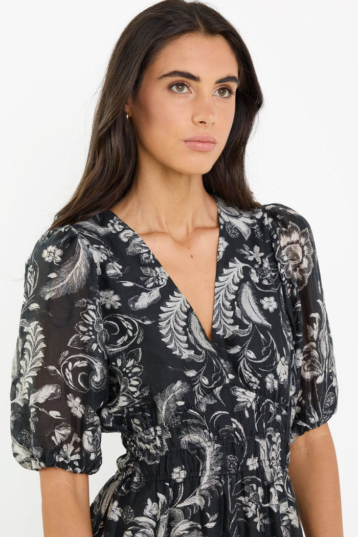 Woman wearing a black floral dress against a white background