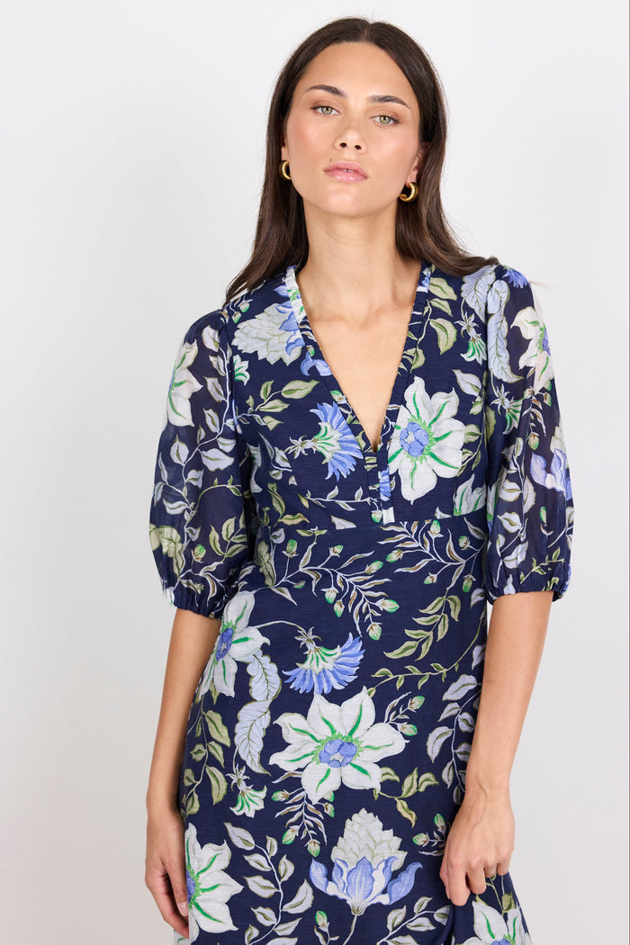 Woman wearing a navy floral dress against a white background
